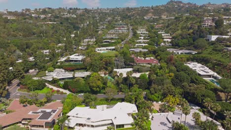 Drone-Flying-Over-Luxury-Beverly-Hills-Homes-Surrounded-by-Lush-Trees-and-Lots-of-Swimming-Pools,-Trousdale-Estates-Neighborhood-on-Sunny-Day