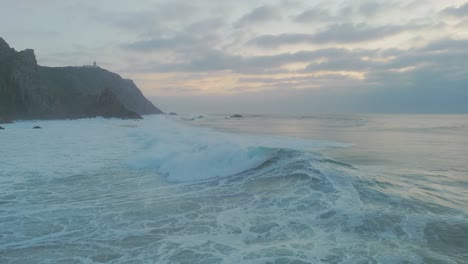 Ocean-wave-breaking-surrounded-by-cliffs-at-sunset