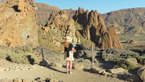 Mother-carrying-baby-and-enjoys-views-of-Tenerife-mountains,-back-view