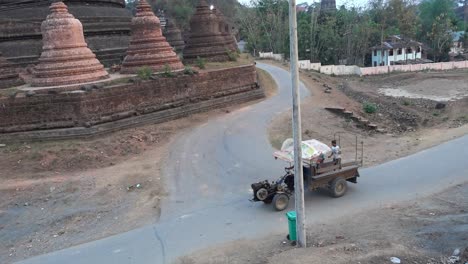 A-tractor-is-passing-by-a-temple-in-mark-u,-Myanmar