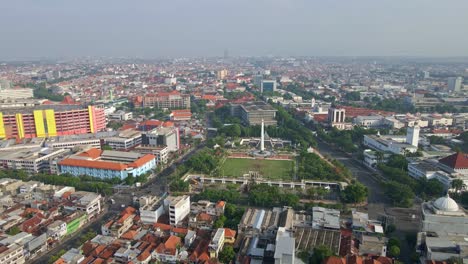 A-stunning-Tugu-Pahlawan,-a-famous-monument-of-heroism-in-Surabaya,-stands-amidst-the-bustling-cityscape-surrounded-by-colonial-architecture-mixed-with-towering-modern-buildings