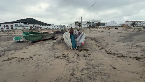 Weathered-fishing-boats-sit-on-the-sandy-shore,-embodying-the-rustic-allure-and-gradual-deterioration-of-equipment-in-a-fishing-village