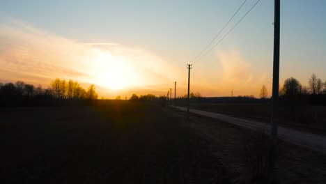 Flying-next-to-electrical-power-line-pole-during-bright-sunset,-Latvia