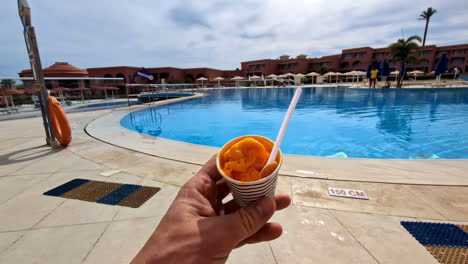 Disfrutando-De-Una-Taza-De-Helado,-Sorbete-O-Sorbete-Junto-A-La-Piscina