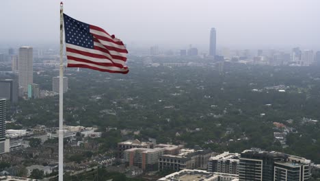 Vista-Por-Drones-De-La-Bandera-Estadounidense-Ondeando-En-La-Cima-Del-Rascacielos-De-Houston