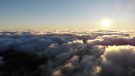 The-drone-captures-the-ethereal-beauty-of-sunrise-on-Pico-Areeiro,-as-clouds-swirl-around-the-mountain-peaks,-painting-the-sky-in-a-breathtaking-display-of-colors