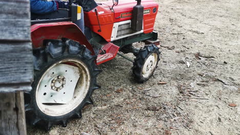 Red-yanmar-m1610d-farming-tractor-pulling-a-stack-of-wooden-planks