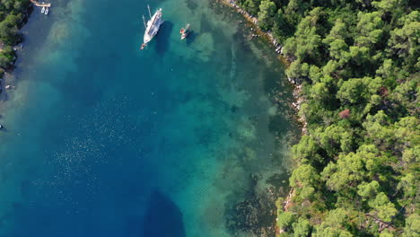 Aerial:-Top-down-shot-of-yacht-anchored-in-famous-crystal-clear-bay-and-turquoise-beach-of-Panormos,-Skopelos-island,-Sporades,-Greece