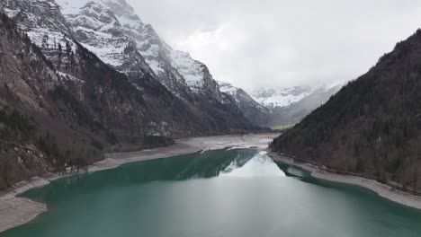 Klöntalersee's-icy-allure-beneath-the-Glärnisch-massif,-Switzerland-alps---aerial