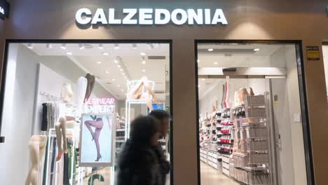 Shoppers-and-pedestrians-walk-past-the-Italian-fashion-legwear,-socks,-and-swimwear-brand,-Calzedonia,-store