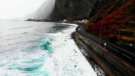 The-drone-captures-a-tumultuous-storm-over-the-ocean-near-the-road,-with-powerful-waves-crashing-against-the-shore,-creating-a-dramatic-and-awe-inspiring-scene