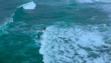 Drone-shot-of-surfers-playing-and-surfing-backwards-during-high-tide-in-Carlsbad-California