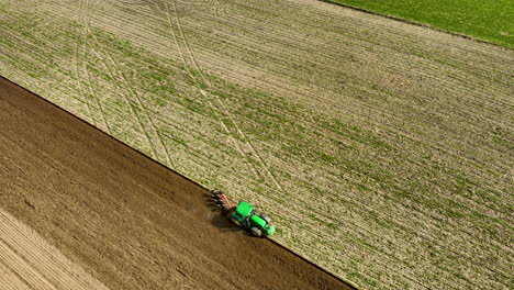 Tractor-Verde-Con-Arado-De-Disco,-Arando-El-Campo-Durante-La-Luz-Del-Sol-En-Primavera