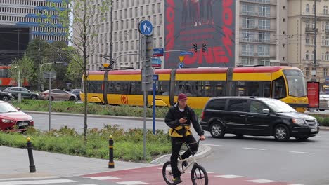 A-scene-depicts-a-pedestrian-area-in-Warsaw,-Poland,-where-a-cyclist-navigates-through-busy-car-traffic,-symbolizing-modernity-and-movement-within-contemporary-architecture