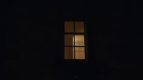 Window-with-light-on-inside,-filmed-from-street-at-night