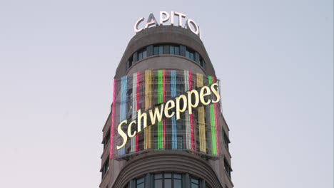 Un-Vibrante-Letrero-De-Neón-De-Schweppes-Adorna-El-Edificio-Carroñero,-Conocido-Como-El-Capitolio,-En-La-Gran-Vía-De-Madrid,-Un-Bullicioso-Centro-De-Entretenimiento-Y-Comercio-Minorista.