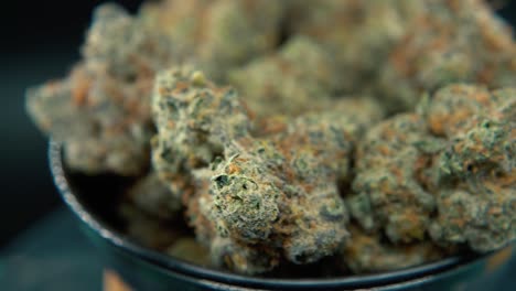 A-macro-dreamy-steady-shot-of-a-cannabis-plant,-hybrid-orange-strains,-sativa-,marijuana-flower,-on-a-rotating-stand,-slow-motion,-4K-video,-studio-lighting