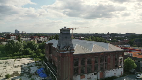 Kreisförmige-Antenne-Eines-Historischen-Verlassenen-Gebäudes-Mit-Uhrturm-Zeigt-Gent-Im-Hintergrund