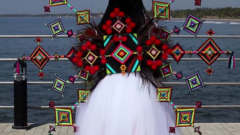 Mujer-De-Espaldas-Con-Vestido-De-Tul-Blanco-Con-Coloridos-Ojos-De-Dios-De-La-Cultura-Wixarika