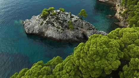 Kalamota-Island,-Adriatic-Sea,-Croatia---A-Scenic-View-of-Crystal-clear-Blue-Waters-and-Verdant-Rock-Cliffs---Aerial-Drone-Shot