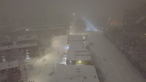 La-Tormenta-De-Nieve-Arrasa-Las-Calles-De-La-Ciudad-De-Montreal-Por-La-Noche,-Con-Las-Farolas-Brillando-Tenuemente-Y-Con-Una-Vista-De-ángulo-Alto