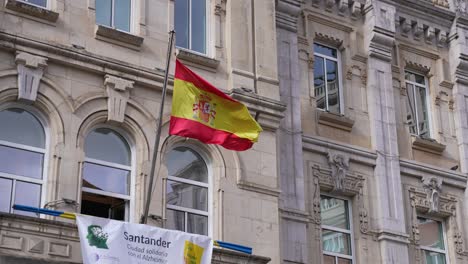 Spanische-Landesflagge-Weht-Auf-Der-Terrasse-Des-Rathauses-Von-Santander,-Nahaufnahme-In-Zeitlupe