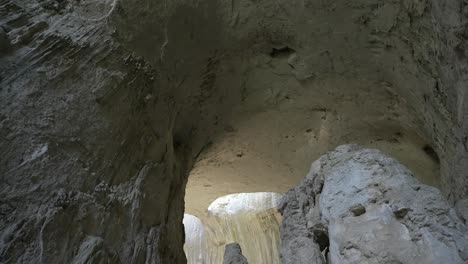 Pedestal-drone-shot-inside-one-of-the-chambers-of-Prohodna-Cave,-showing-the-two-holes-more-commonly-known-as-God's-Eyes,-located-in-Karlukovo,-in-Bulgaria