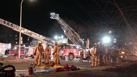 Brigada-De-Bomberos-Parados-En-La-Calle-Después-De-Extinguir-El-Incendio-En-Un-Edificio-Por-La-Noche-En-Montreal,-Canadá