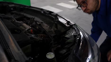 Mechanic-at-work-refilling-car-windshield-wiper-fluid-at-automotive-shop