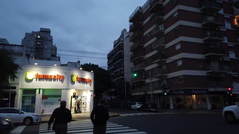 Farmacity-Apotheke,-Berühmter-Convenience-Store,-Eingang-Zum-Stadtviertel-Buenos-Aires,-Abendnacht,-Autos,-Fußgänger,-Die-An-Gebäuden-Vorbeigehen,-Skyline