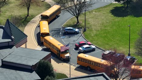 Amerikanische-Schulszene-Mit-Traditionellen-Gelben-Schulbussen,-Die-Im-Frühling-Am-Eingang-Der-Schule-Parken