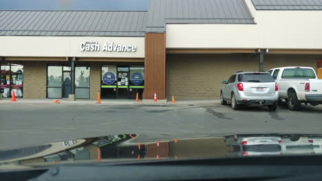 Red-pickup-truck-passing-by-in-parking-lot-near-storefront,-POV-shot