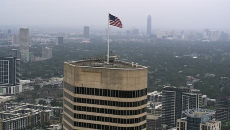 Vista-Por-Drones-De-La-Bandera-Estadounidense-Ondeando-En-La-Cima-Del-Rascacielos-De-Houston