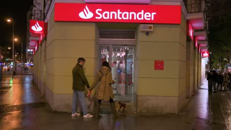 Fußgänger-Gehen-Nachts-An-Der-Spanischen-Multinationalen-Geschäftsbank-Und-Den-Finanzdienstleistungen-Der-Santander-Filiale-Vorbei