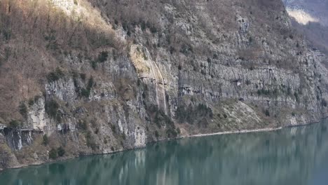 La-Serena-Belleza-De-Quinten,-Suiza,-A-Vista-De-Pájaro-Con-Estas-Impresionantes-Imágenes-De-Drones,-La-Luz-Del-Sol-A-Través-De-La-Montaña-Y-Se-Refleja-En-Las-Tranquilas-Aguas-Del-Río-Walensee.