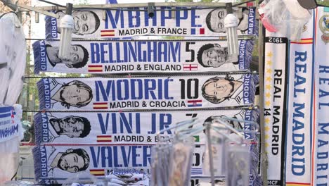 Bufandas-Temáticas-Del-Real-Madrid,-Incluido-El-Diseño-De-Kylian-Mbappé,-Se-Ven-A-La-Venta-Cerca-Del-Estadio-Santiago-Bernabéu-Durante-El-Partido-De-Fútbol-De-La-Liga-De-Campeones-Contra-El-Manchester-City.