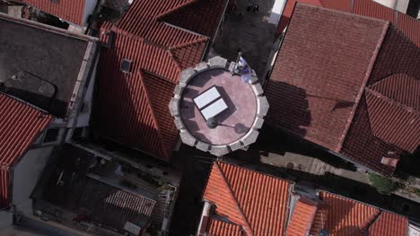 Vista-Aérea-De-Arriba-Hacia-Abajo-De-La-Torre-Del-Reloj-Sahat-Kula-Y-La-Bandera-De-La-Ciudad-De-Herceg-Novi,-Montenegro