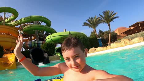Little-Boy-On-Inflatable-Floater-Coming-Out-From-Slide-To-The-Swimming-Pool-In-Marsa-Alam,-Egypt
