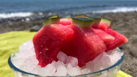 Juicy-fresh-cut-watermelon-triangles-on-ice-at-the-beach-in-Marbella-Estepona-Spain,-healthy-hot-summer-day-snack-by-the-sea,-holiday-vacation,-4K-static-shot