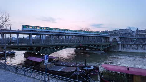 Train-passing-on-Bir-Hakeim-bridge-crossing-Seine-river,-Paris-at-sunset,-France