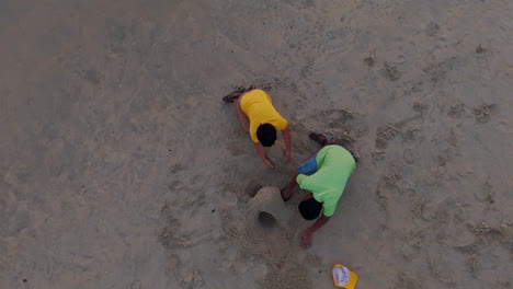 Hermanos-Jugando-En-La-Playa,-Niños-Jugando-Con-Arena-Al-Atardecer