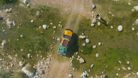 Aerial-Birds-Eye-View-Of-Person-Cleaning-Parked-4x4-Truck-In-Arid-Landscape-In-Sindh