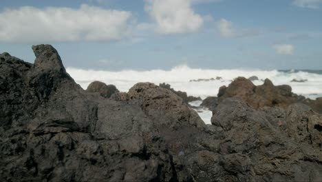 Slowmotion-sharp-volcanic-rocks-foreground,-crushing-ocean-waves-near-Punta-Negra,-Buenavista-del-Norte,-Tenerife,-Canary-Islands-in-spring