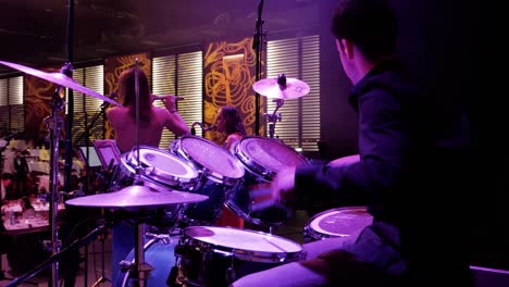 Un-Baterista-Musical-En-El-Escenario-Durante-Una-Noche-De-Gala-Estudiantil,-Golpea-Su-Batería-Con-Sus-Baquetas.