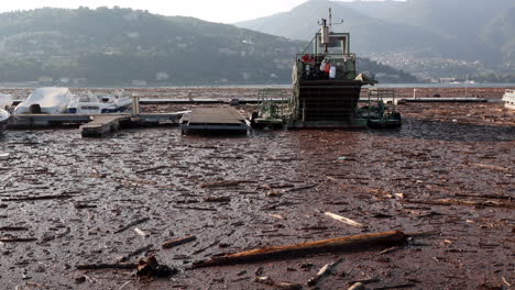 Como,-Italien---29.-Juli-2021---Boote,-Die-Auf-Dem-See-Treiben,-Bedeckt-Mit-Holz-Und-Trümmern-Nach-Heftigen-Regenfällen,-Die-In-Der-Gegend-Schwere-Schäden-Verursachten