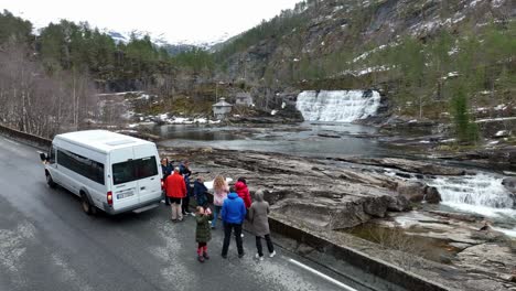 Tourists-exit-white-minibus-to-look-at-waterfall-during-springtime