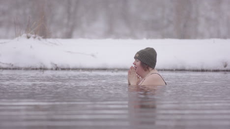 Two-ice-bathers-sitting-in-a-frozen-lake,-Swedish-winter,-PAN-shot