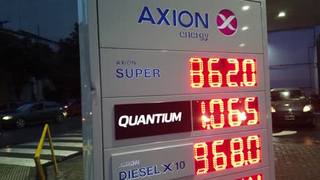Closeup-sign-price-display-of-oil-petrol-Axion-company-at-latin-american-night-streets,-car-fuel-value-per-liter-in-buenos-aires-city,-caballito-neighborhood-argentina