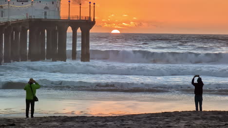 Turistas-Tomando-Fotos-De-Una-Hermosa-Puesta-De-Sol-En-La-Playa,-Disfrutando-El-Momento