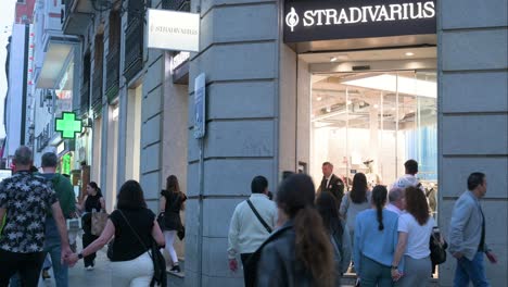 Compradores-Y-Peatones-Pasan-Por-La-Tienda-De-Moda-Española-De-Ropa-Femenina-De-España-Propiedad-Del-Grupo-Inditex,-Stradivarius,-Durante-La-Noche.